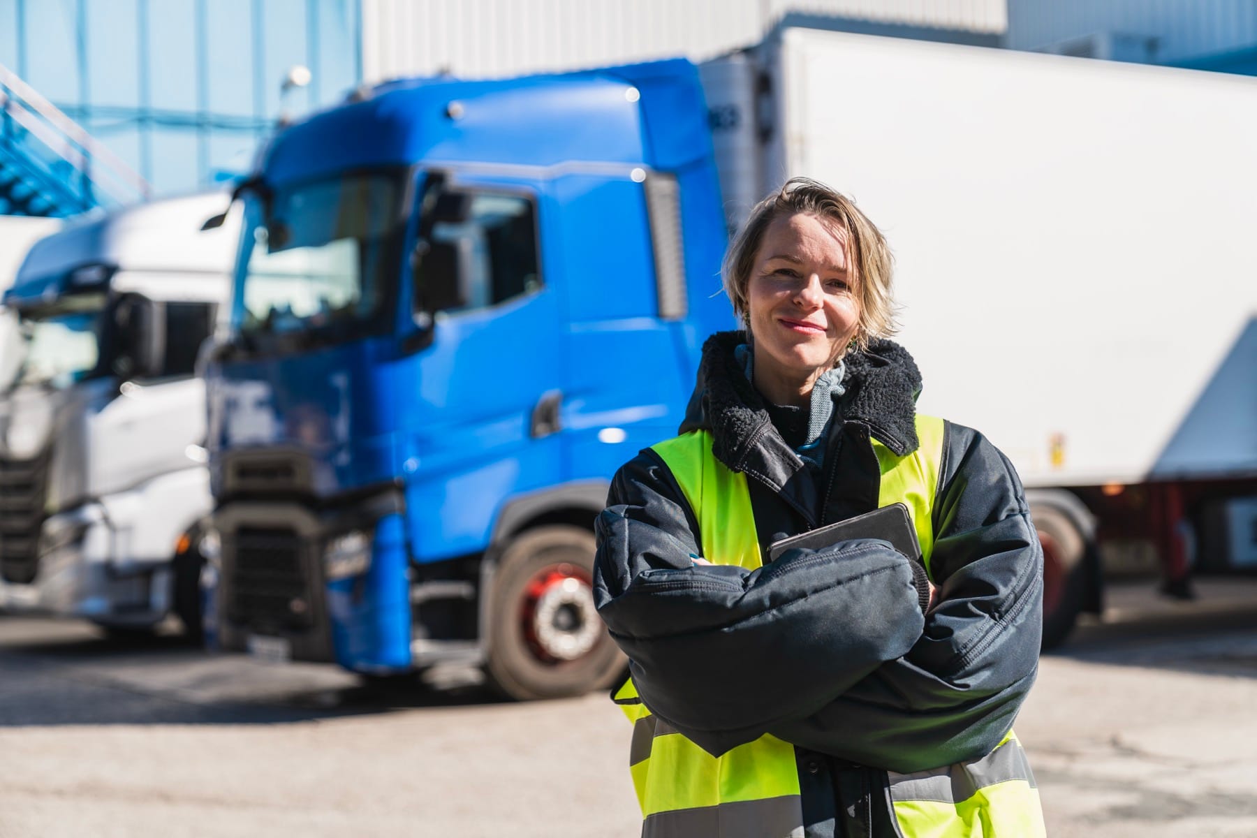 Haulage operator in a hi-vis jacket holding a tablet in front of a container lorry