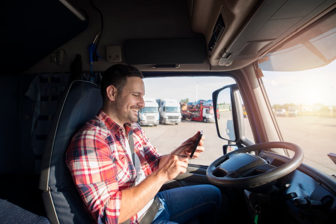 Truck driver confirming a delivery job on his phone from the cab