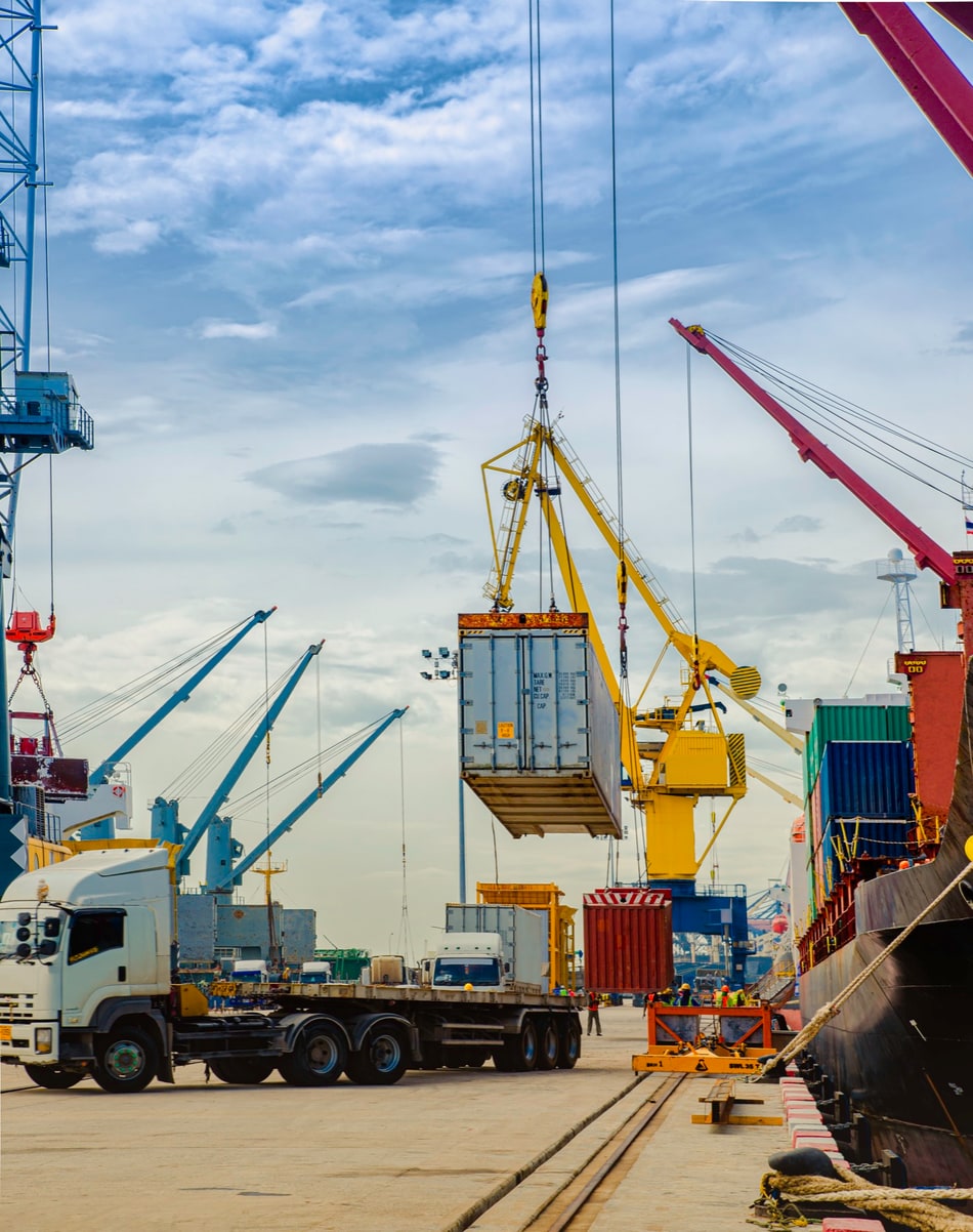 Quayside crane lifting a shipping container onto a flatbed truck at port
